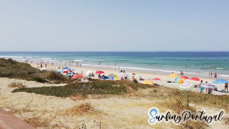 São Torpes beach on a summer day, with some surfers in the water