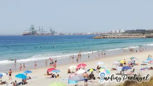 São Torpes beach on a summer day, with some surfers in the water