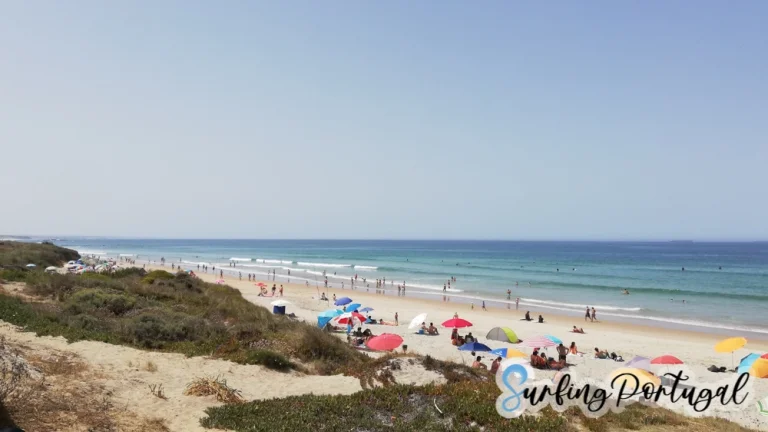 São Torpes beach on a summer day, with some surfers in the water
