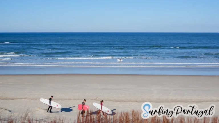 Surfers in the water at Peniche Cerro and some surfers walking with boards on the sand