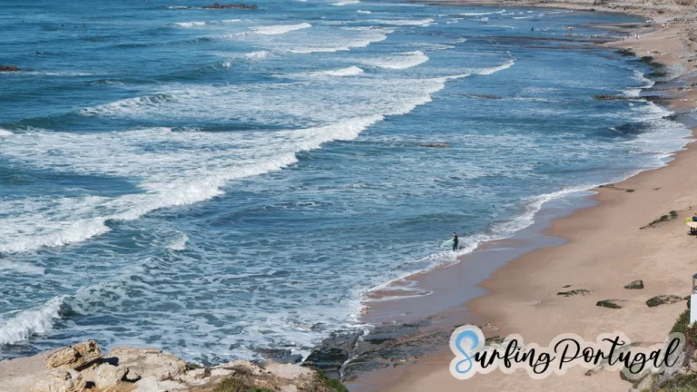 Panoramic view of Praia de São Sebastião, Ericeira, with a surfer entering the water